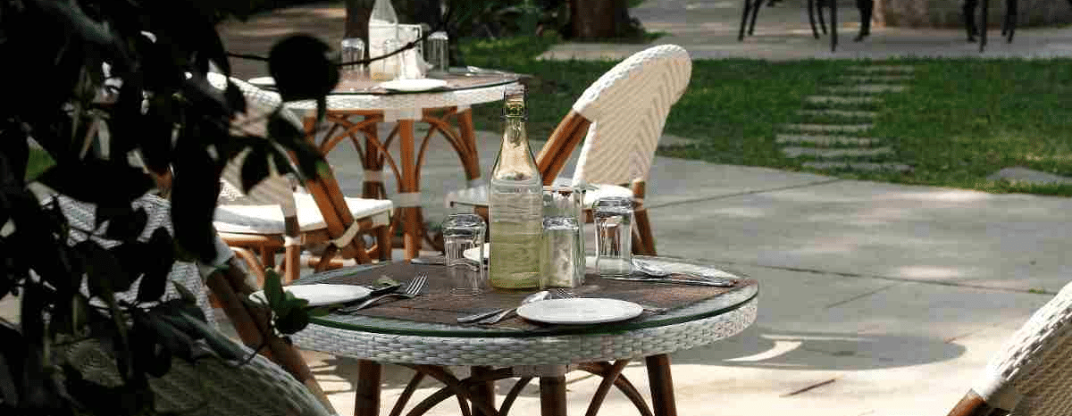 Outdoor patio dining area with elegant table settings and wicker chairs at Amanvana Spa Resort, Coorg.