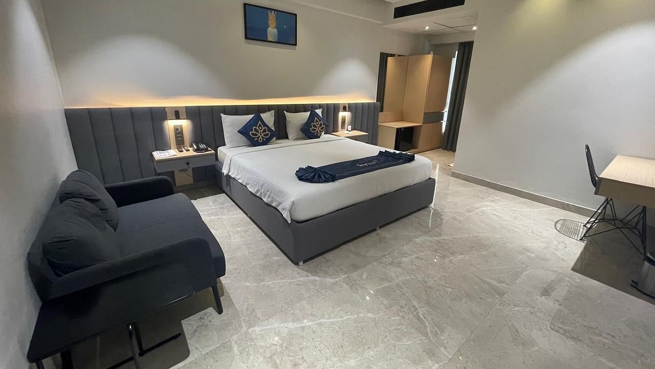 Suite featuring a large bed, cosy seating area, work desk, and modern decor with marble flooring at Hotel Kyzen, Hitech City.