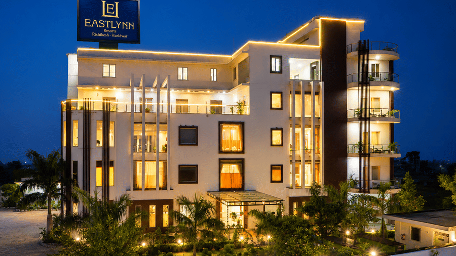 Multi storey hotel exterior lit up against the night sky at Eastlynn Resort, Rishikesh.