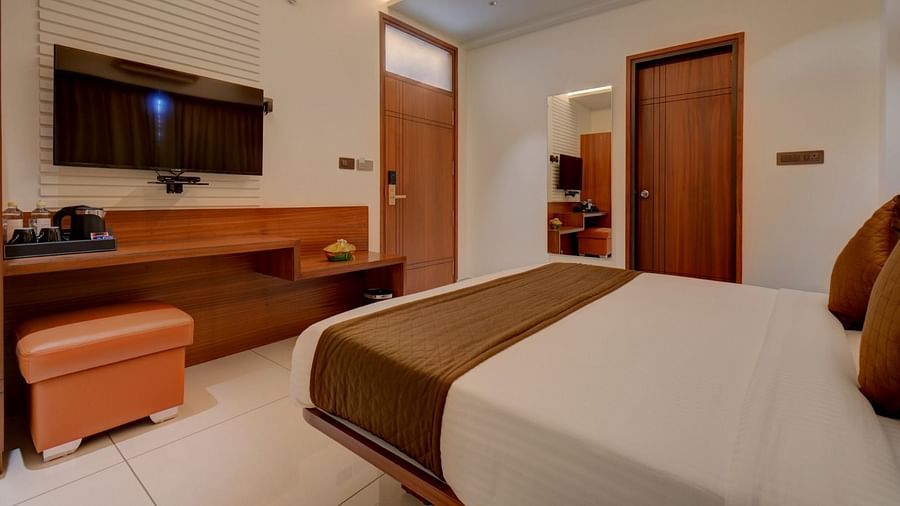 A side view of a room featuring a bed with a television positioned in front at Hari Govindas, Siddappa Square.