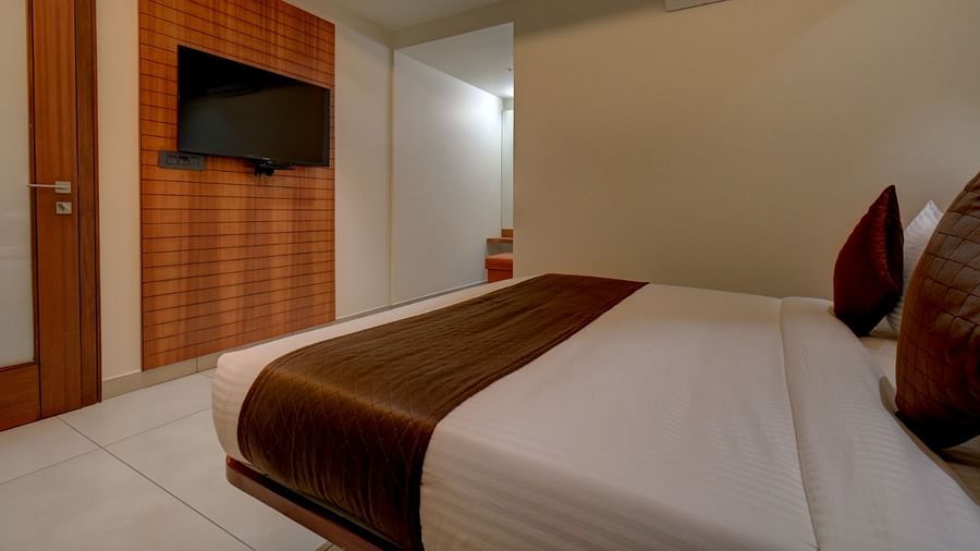 Side view of a room with a bed and a television in front of it at Hari Govindas, Siddapa Square.