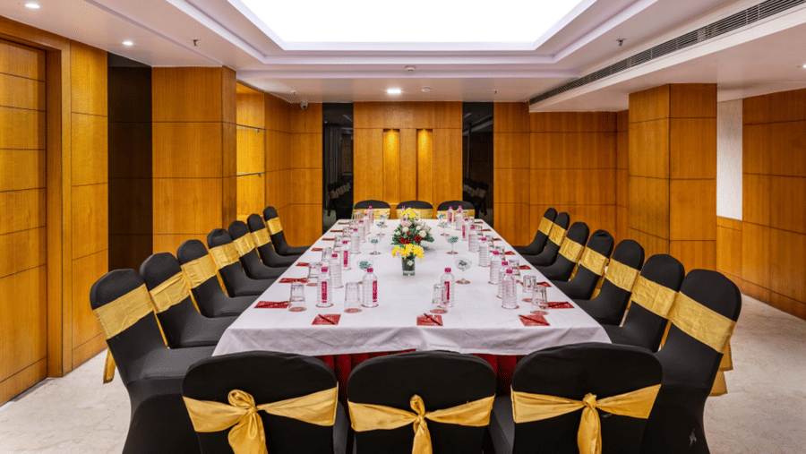 a boardroom meeting arrangement at a Banquet hall in Libra Lords Inn Jaipur with wood-panelled walls and ceiling lights