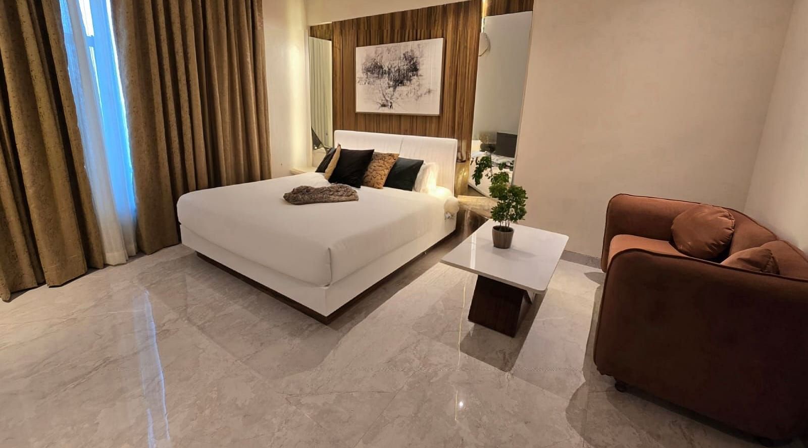 A cosy bedroom with a potted plant placed on a small table between the bed and the sofa at Hotel Mumbai House, Vashi.