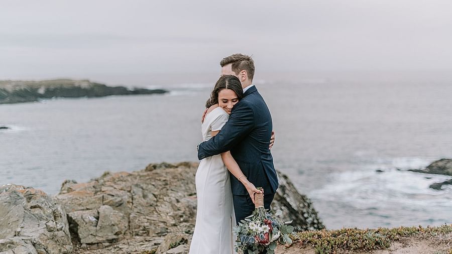 A couple embracing each other on a cliff by the ocean
