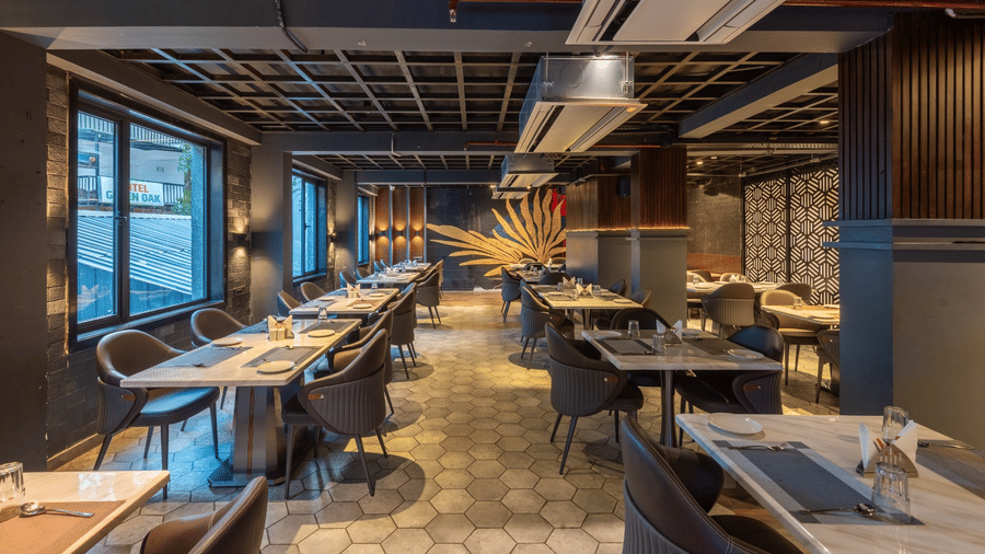 A dining area with wooden tables, dark chairs, and large windows overlooking an outdoor view | Lawrence Solitaire Resort, Nainital