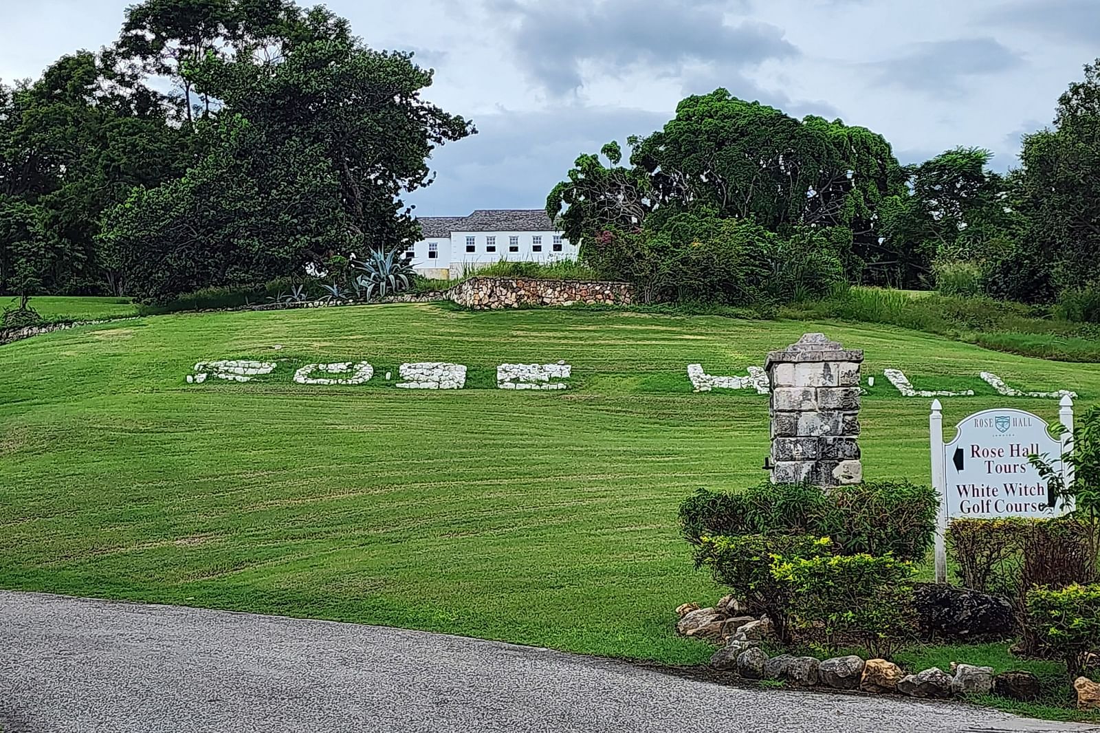 image of the rose hall great hall with a lush green lawn in front of it with a signage.