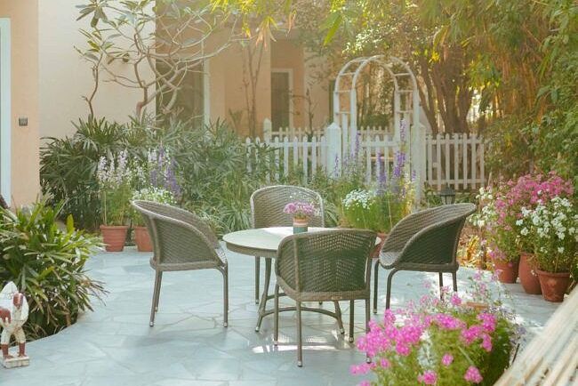 Outdoor patio seating area with metal chairs and a table near flowering plants and garden decor at Karma Chalets.