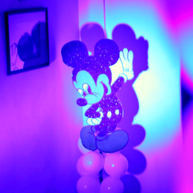 Kids party decoration at The Bristol Hotel, Gurgaon with an illuminated cartoon cutout on a column of white balloons lit with blue and purple light.