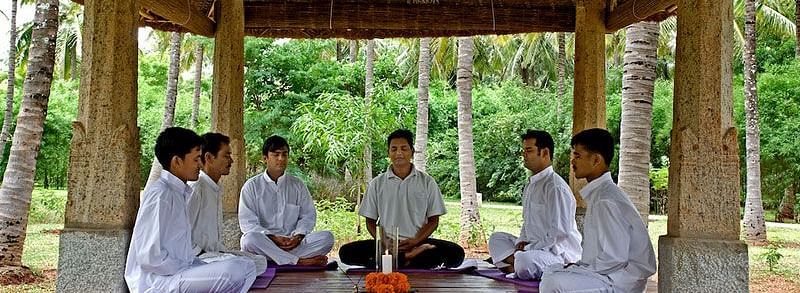 People sitting on cushions under a wooden gazebo, outdoor setting, group activity - Shreyas Retreat