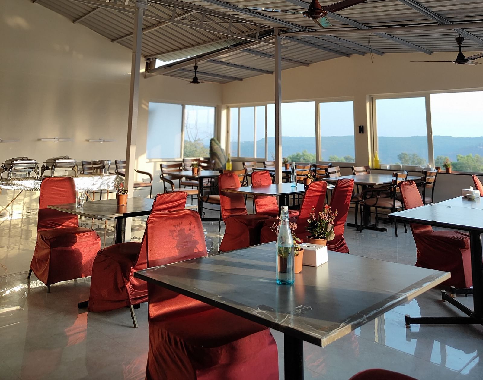 The interior of a dining area with metal beams and red chairs.