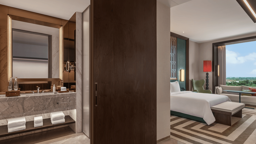 Club Room 8012 bathroom with a washbasin, mirror and adjoining bedroom view at The Residency Signature Madurai.