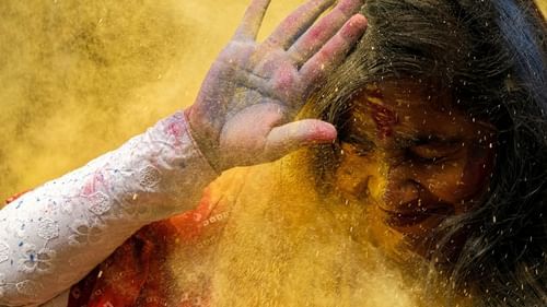 a girl unsuccessfully shielding herself from holi colours with her palm covering her face