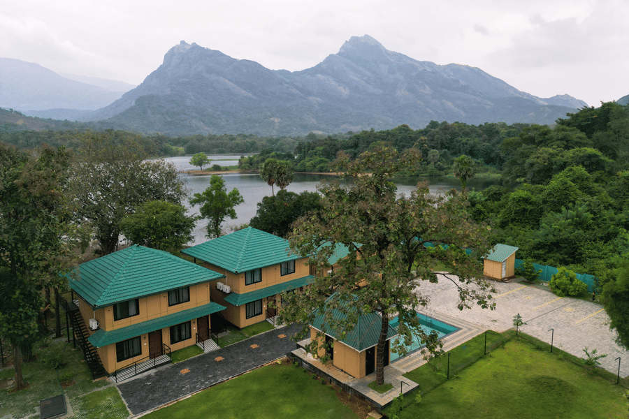 High-angle landscape view of the resort buildings situated between a calm lake and towering mountain peaks - Ibex Resorts, Malampuzha (Kava Eco Camp and Caravan Park)