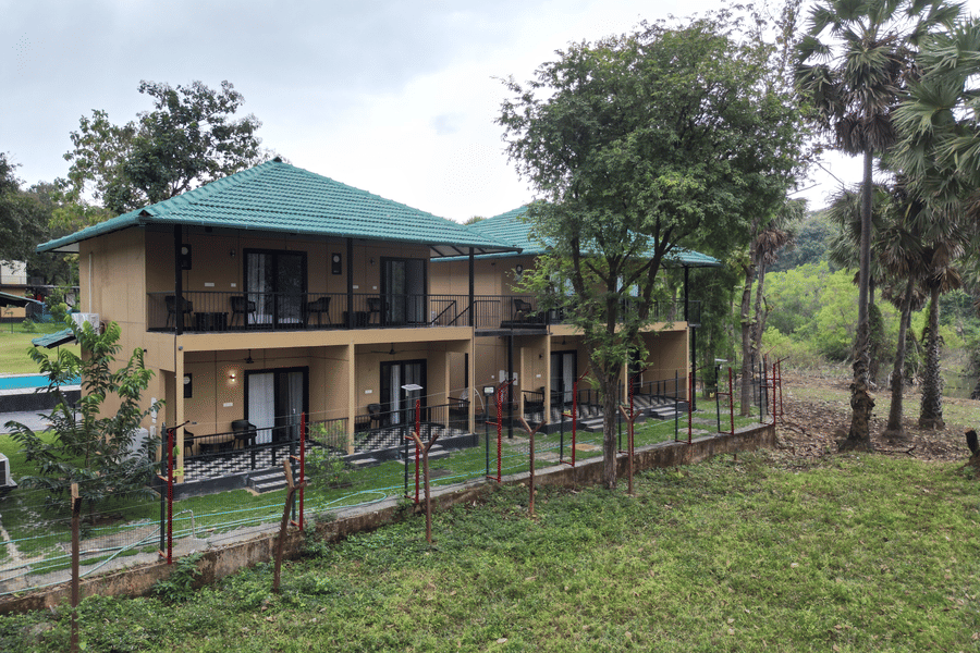 2-storey resort building with private balconies surrounded by a lush natural landscape and tall trees - Ibex Resorts, Malampuzha (Kava Eco Camp and Caravan Park)