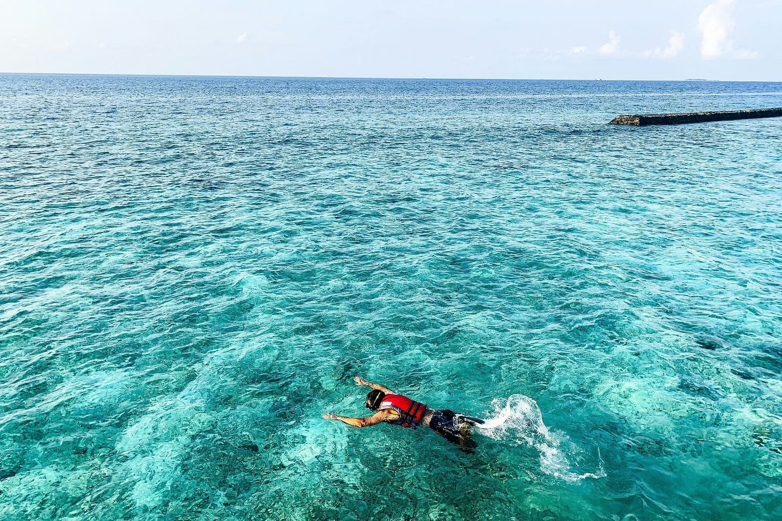 Snorkeler gliding through clear turquoise waters with a tropical backdrop