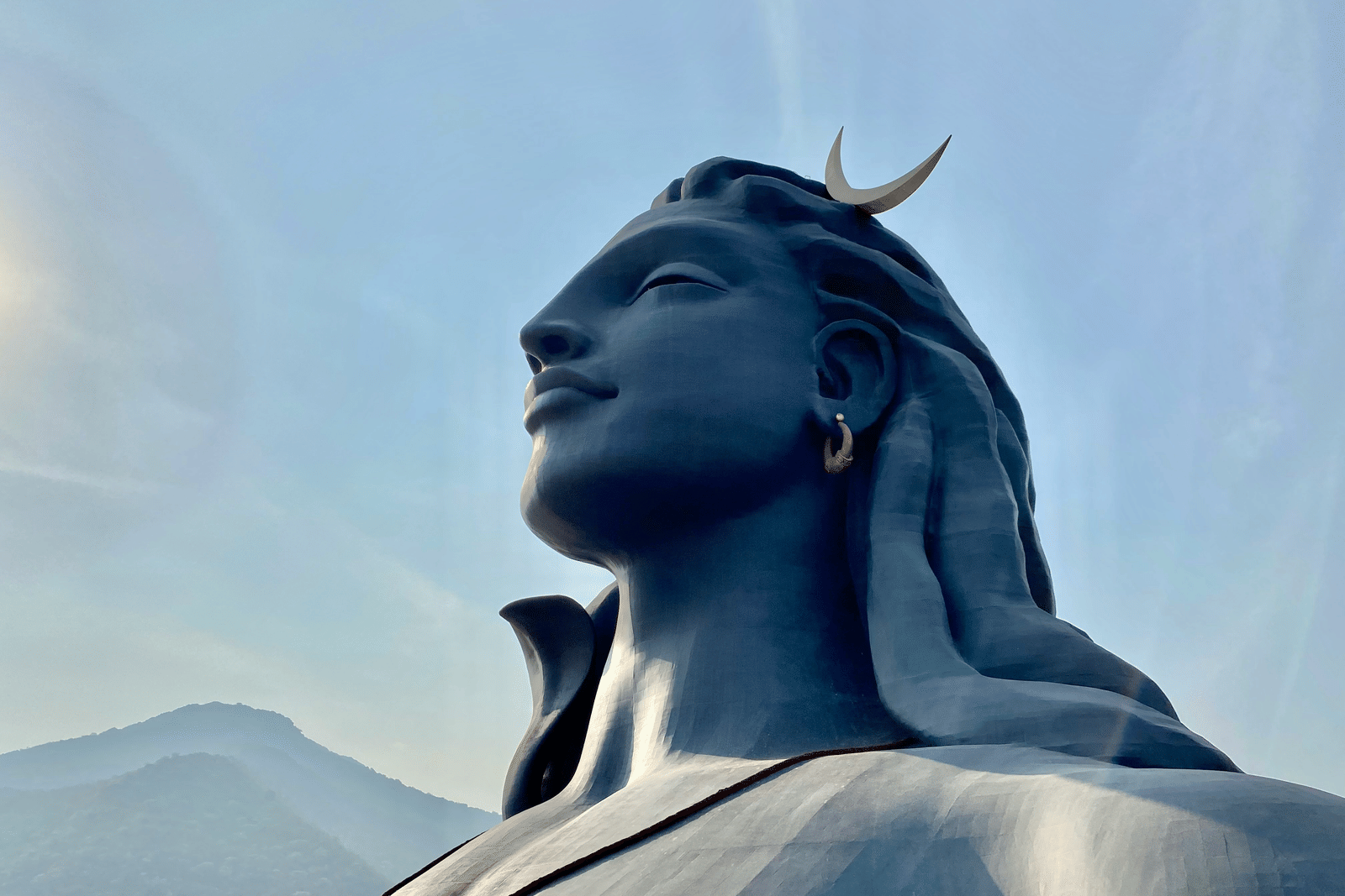 A huge, stunning black stone statue of lord Shiva looking up to the sky.