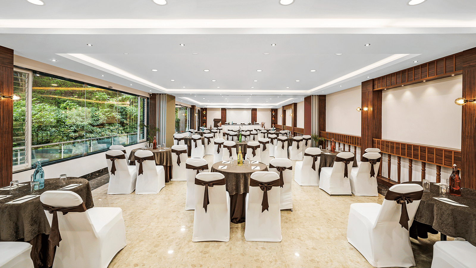 An image of a banquet space which is brightly lit with seating arrangement - GReaT Trails Kodaikanal By GRT Hotels