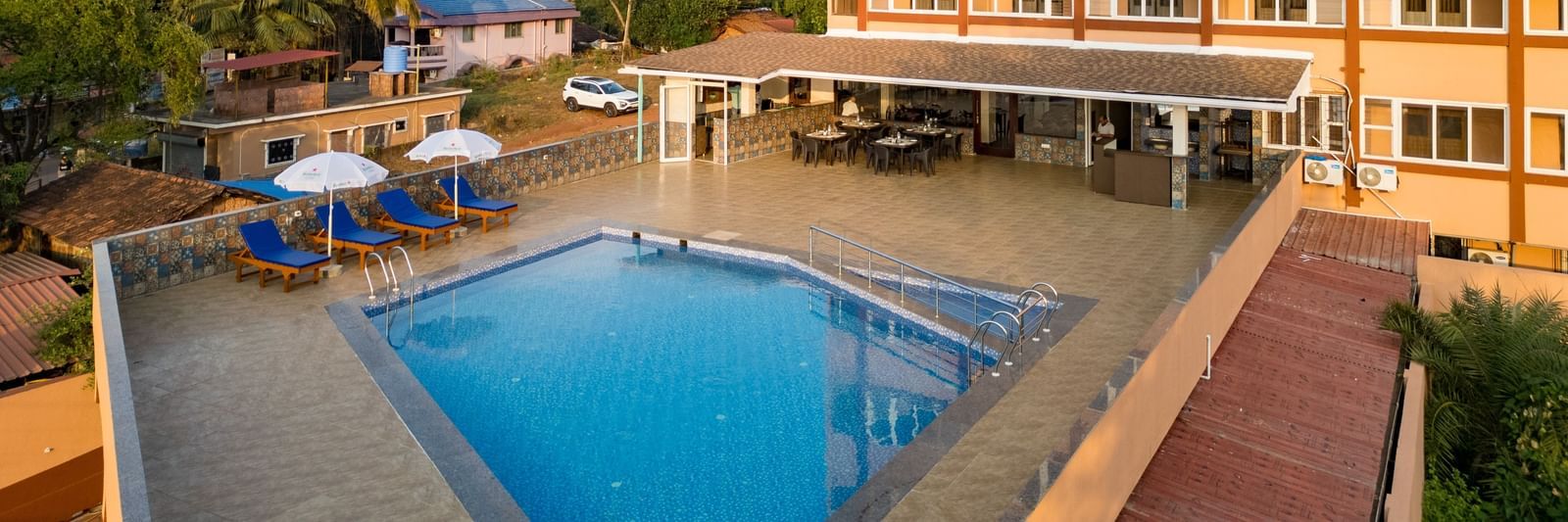 A serene view of the outdoor swimming pool surrounded by sun loungers and palm trees at Nazri The Verda, Arambol.