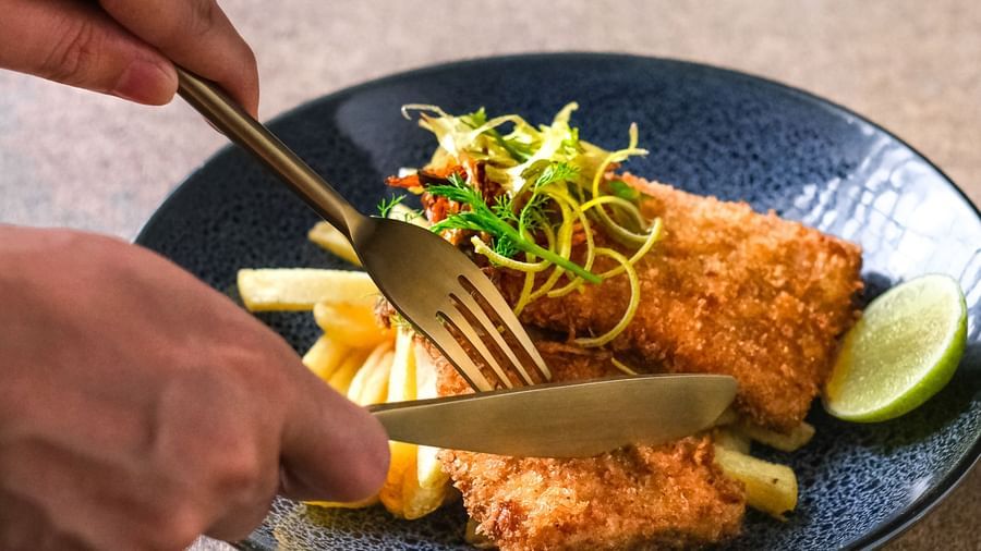 A person digging into a plate of Fish and Chips | Mango Hill, Pondicherry