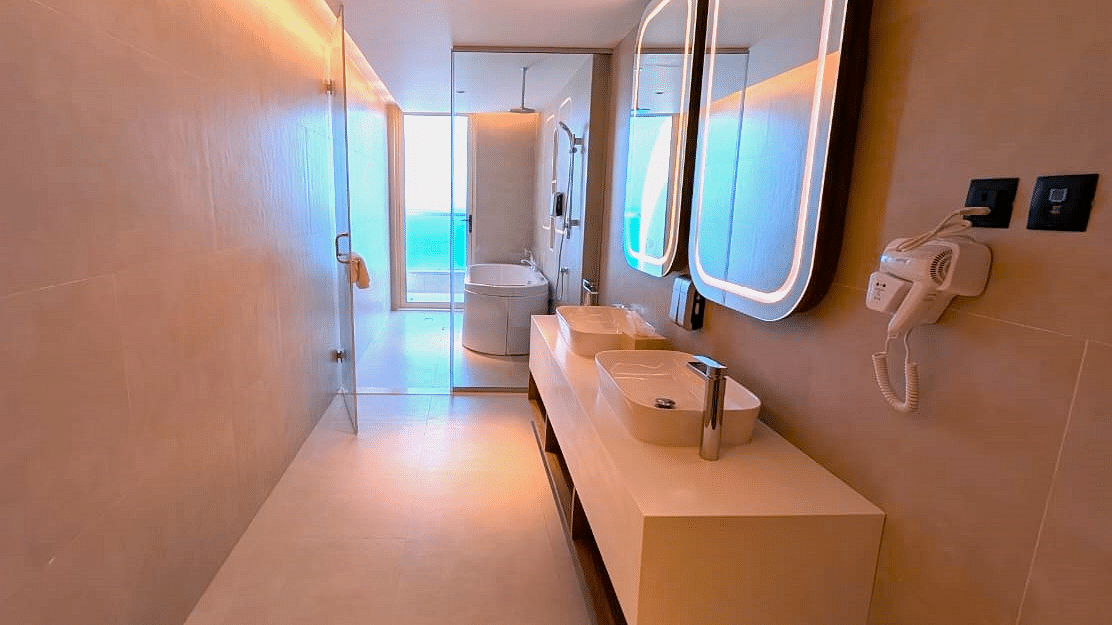 A narrow bathroom at Swosti Premium Beach Resorts, Puri, with double sinks and a long mirror.