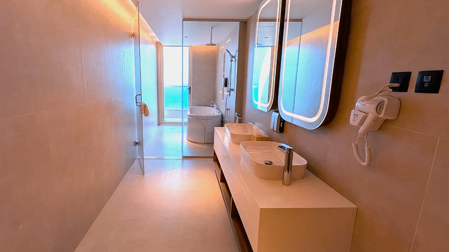 A narrow bathroom at Swosti Premium Beach Resorts, Puri, with double sinks and a long mirror.