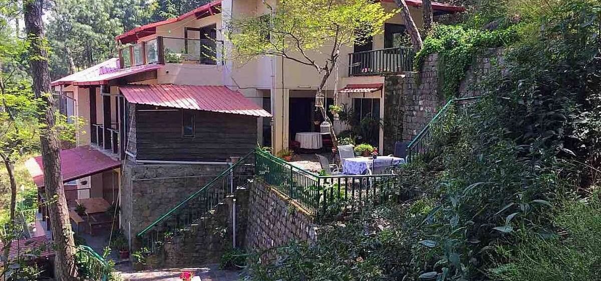 Facade view of SOUTHGATE KASAULI BY ZENQ with bush covering them at the front. 