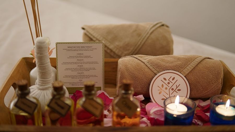 A pair of candles placed alongside some essential oils and towels on a tray in a spa