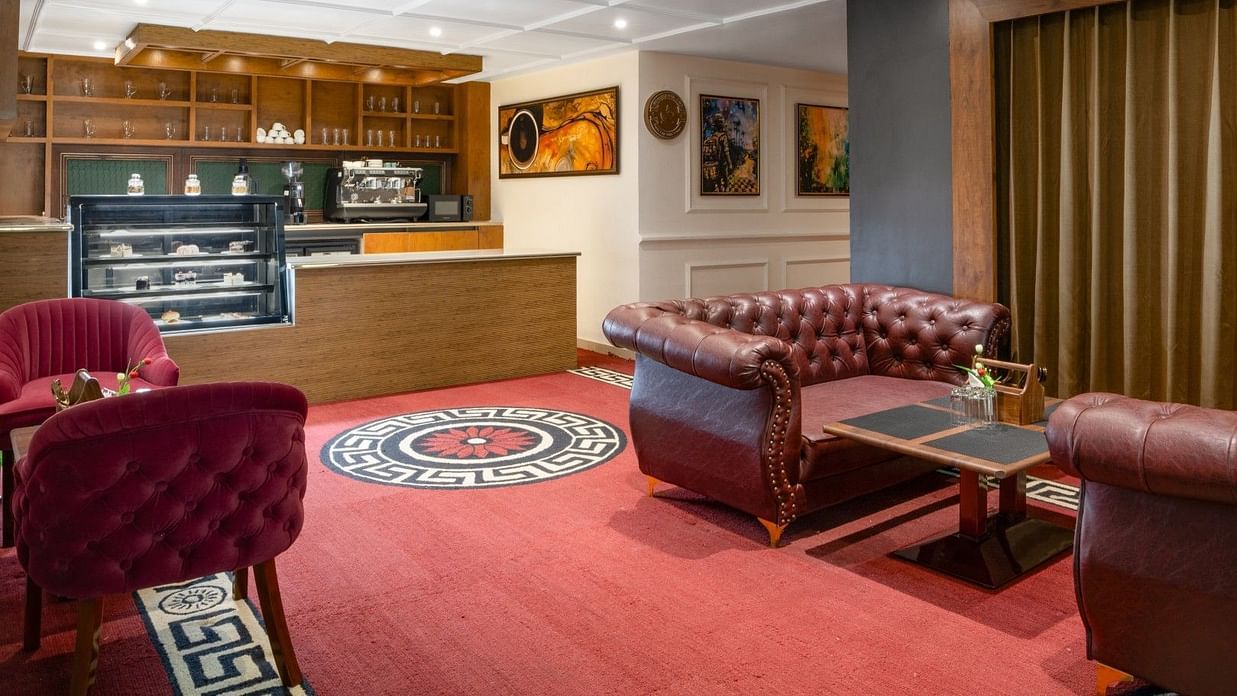 A cafe area at Clarks Inn, Basti, with a service counter, a display case, and seating including a leather tufted sofa.