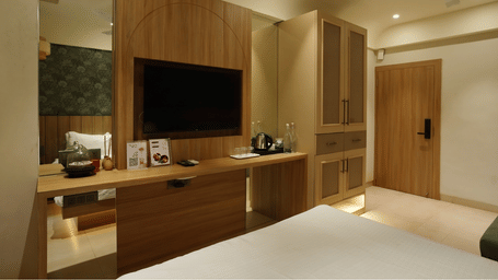 A room featuring wall mounted television, a wooden wardrobe, and a mirror at Bougainvillea, Alibaug.