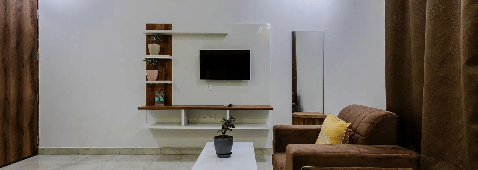 A living area with a sofa set, white centre table, and a television unit against the wall - Lime Tree Hotels & Banquet, Vrindavan