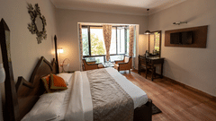 Side view of the cosy bed and a wide window at Himalaya Hotel, Nainital