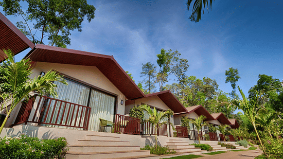 A bright daytime view of the Premium Cottage with a well-maintained pathway and tropical landscaping.