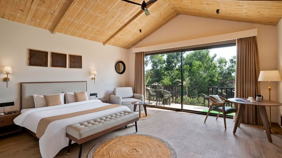 A spacious Premium Cottage room with modern decor, natural lighting, and a balcony overlooking nature.