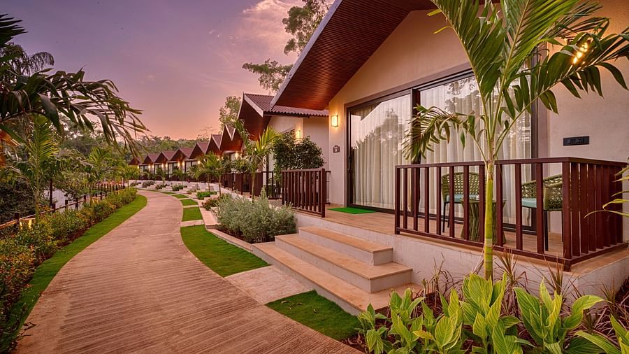 A beautifully landscaped pathway leading to the Premium Cottage, with a vibrant sunset sky in the background.