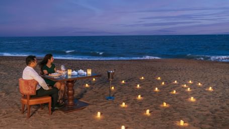 A romantic candlelight dinner setup on a pristine sandy beach – Kaldan Samudra Palace, one of the top 5 Star Restaurants in Mahabalipuram ECR, offering an unforgettable dining experience by the sea