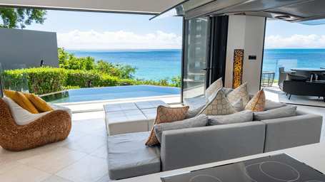 A living area with a sofa, a lounge chair, a balcony featuring a pool view, an ocean view and greenery at Tamarind Hills Resort and Villas - Antigua