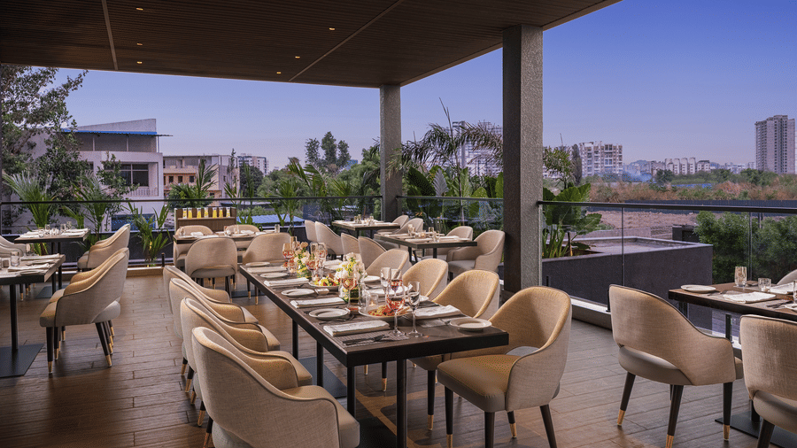 Dining area at Citron Bar with comfortable seating at Essentia Premiere, Pune, with the backdrop of evening sky