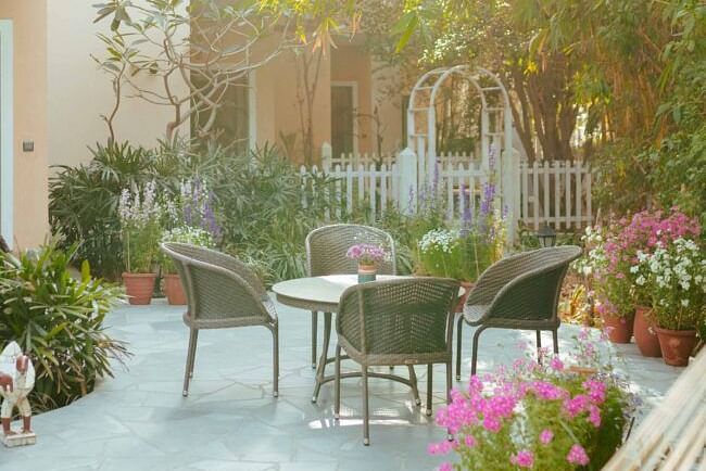 Outdoor seating area with two chairs and a table placed on a stone patio near flowering plants at Karma Chalets.
