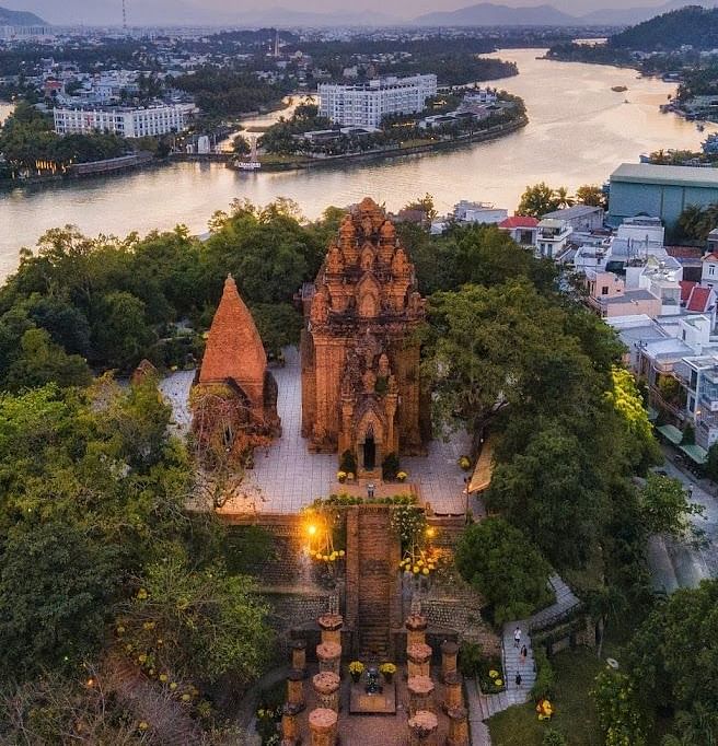 An aerial of a monumental structure covered with trees ans has a small river flowing behind it -  Alibu Resort Nha Thrang