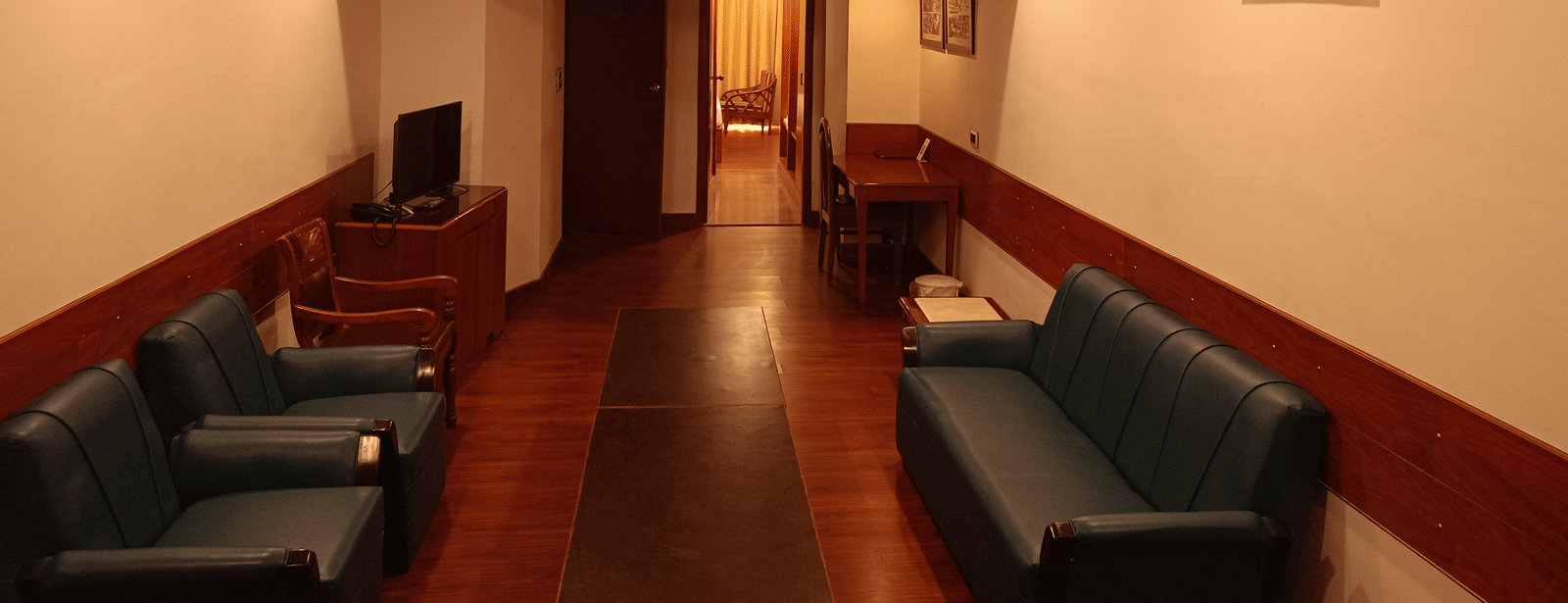 Lounge space at Hotel Gold, Panipat with sofas, a center table, and framed artwork on the walls.