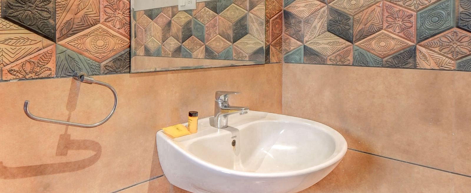 A washroom at Harigovinda's JNStay with a wall-mounted mirror and a washbasin below it