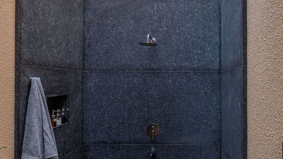 A narrow passageway with dark walls and a stone floor, plants visible at the end - Shreyas Retreat