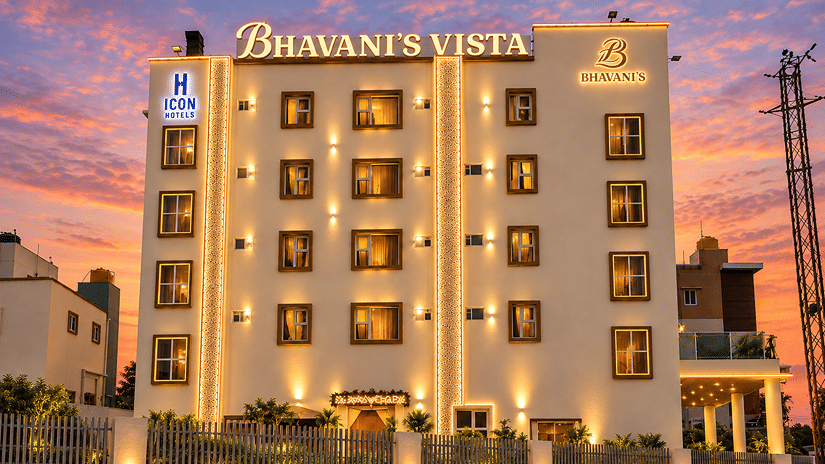 Multi-storey hotel building brightly lit against a dramatic sunset background at Bhavani's Vista By Icon, Hosur. 