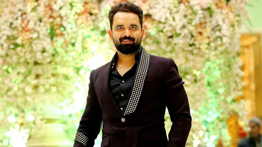 a man in black suit standing in front of a decorated background