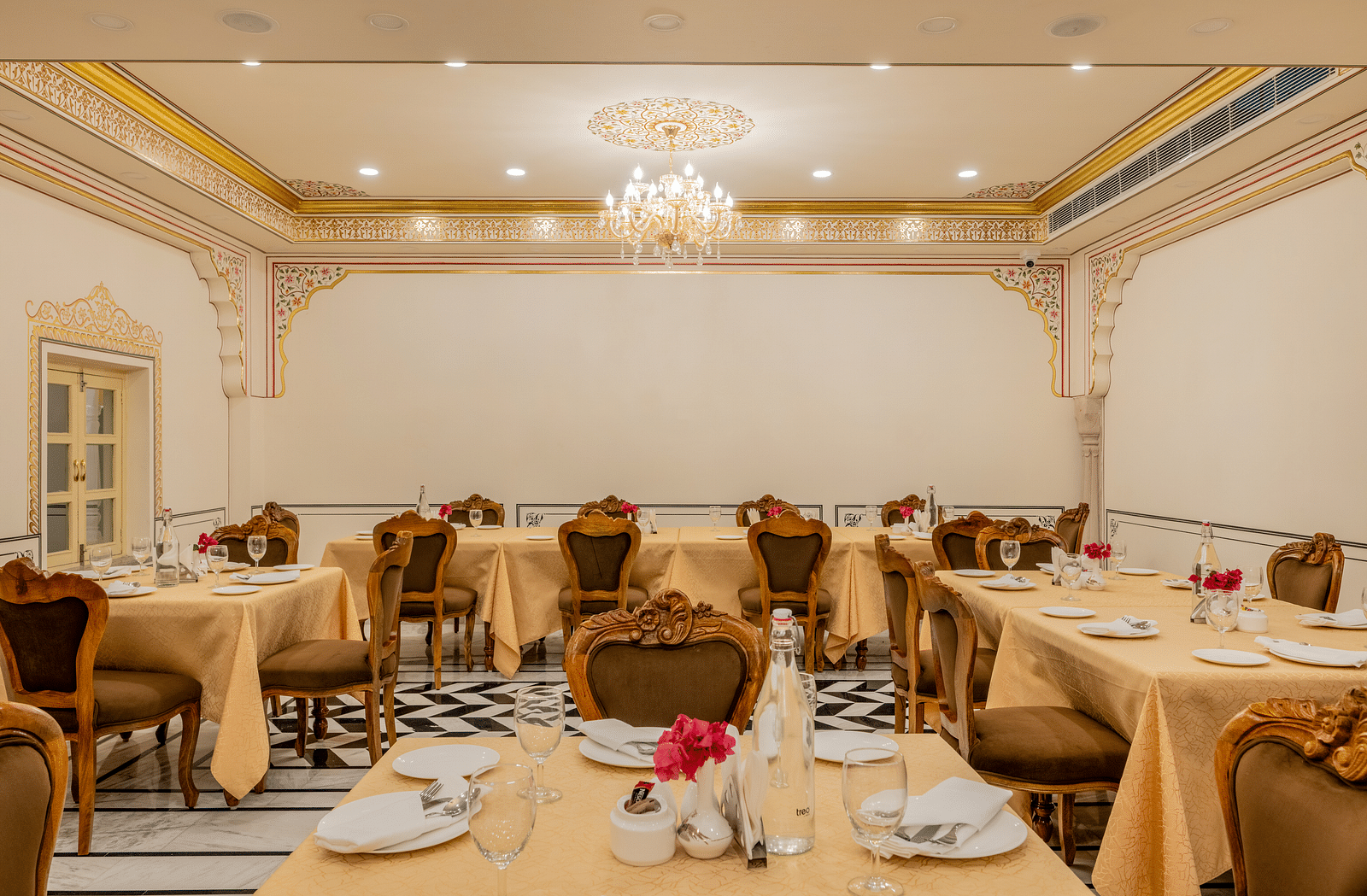 well set dining tables with beige coloured table cloth spread across - Brij Castle, Jaipur