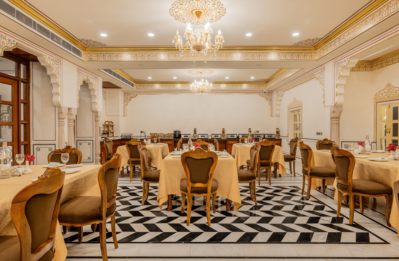 full view image of the dining area with arched hallways with beautiful wooden doors and golden borders in the ceiling - Brij Castle, Jaipur