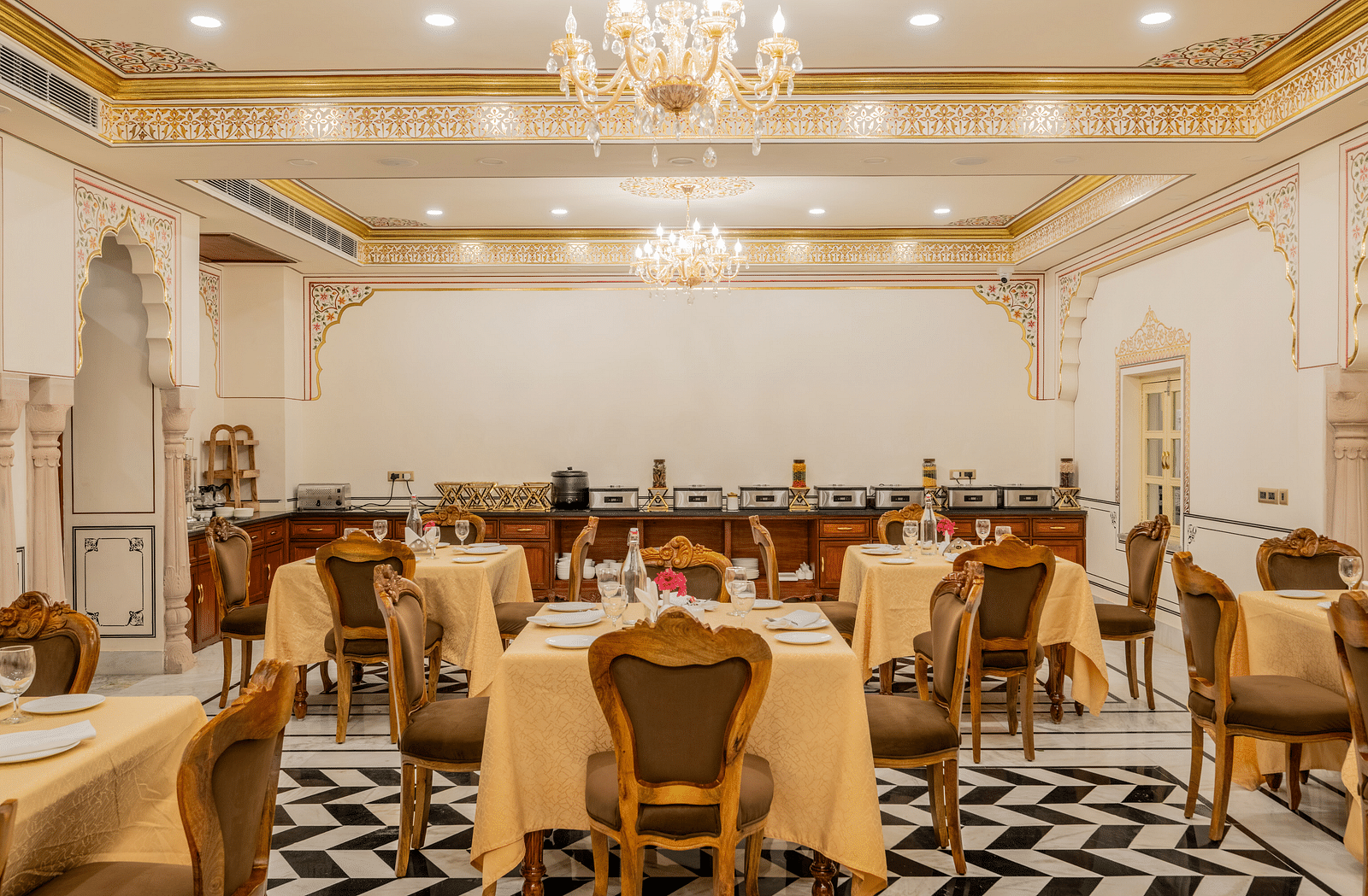 dining tables with royal cushioned chairs surrounding them with rajasthani inspired architecture - Brij Castle, Jaipur