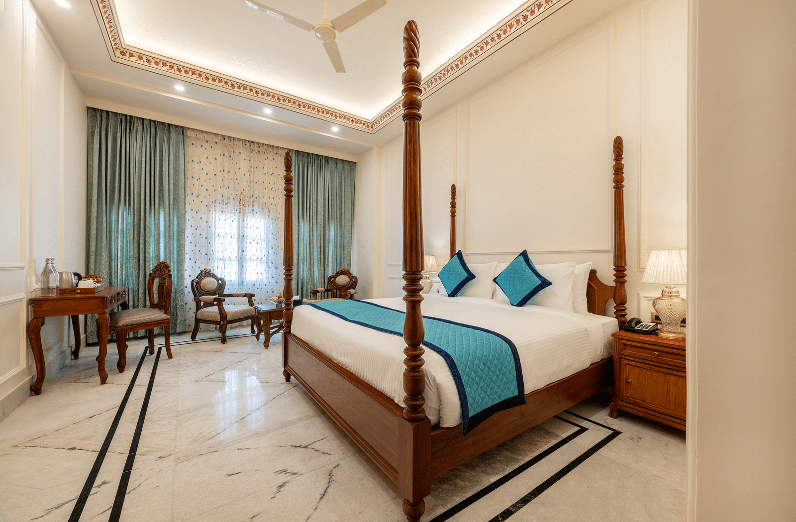 full view image of a room featuring a regal double bed with blue cushions kept over it - Brij Castle, Jaipur