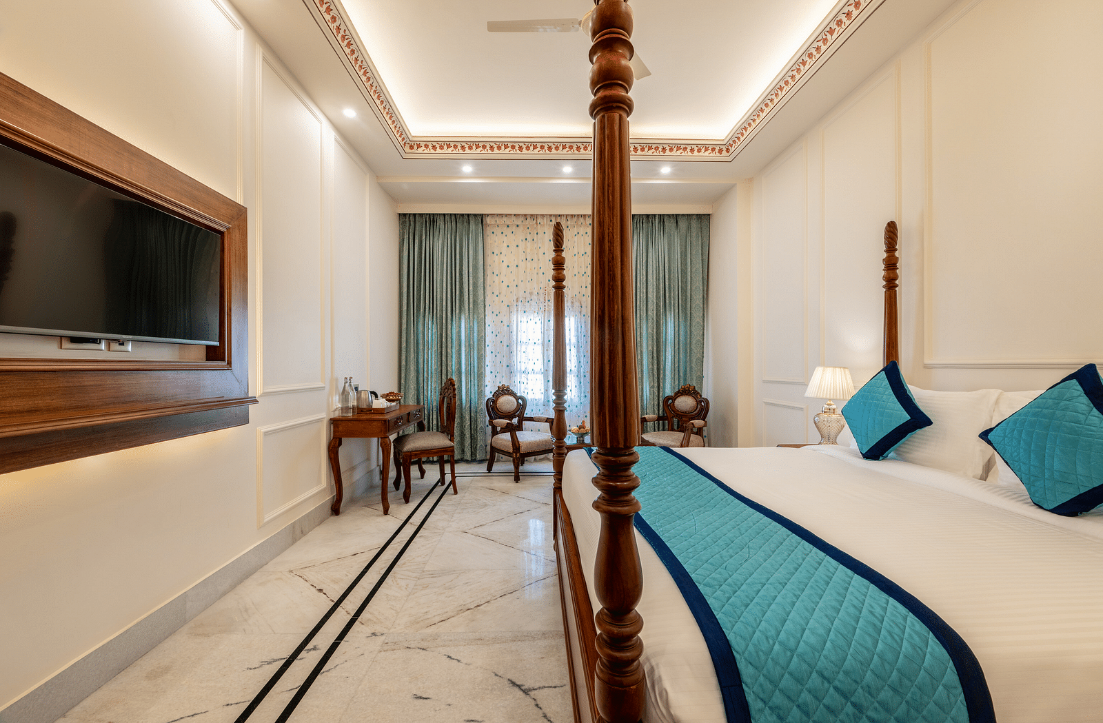a luxurious and well ventilated bedroom featuring a double bed along with a common seating area at the far end of the room - Brij Castle, Jaipur