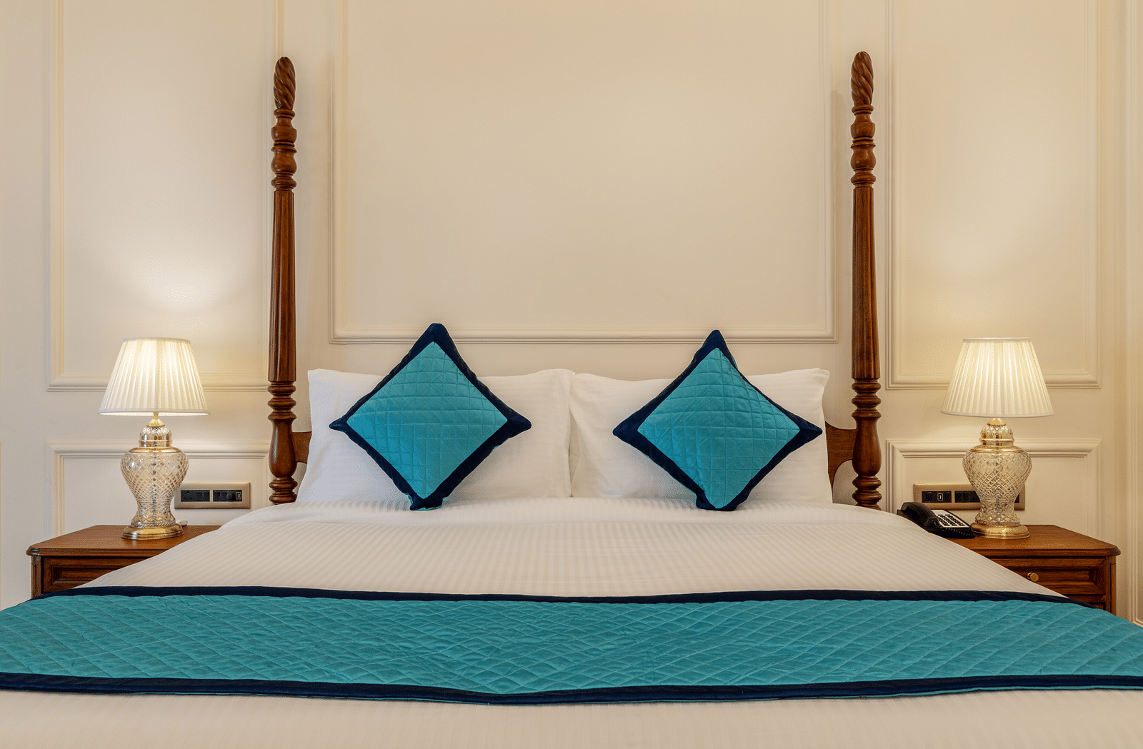 close up image of a double bed with two blue cushions kept over it - Brij Castle, Jaipur